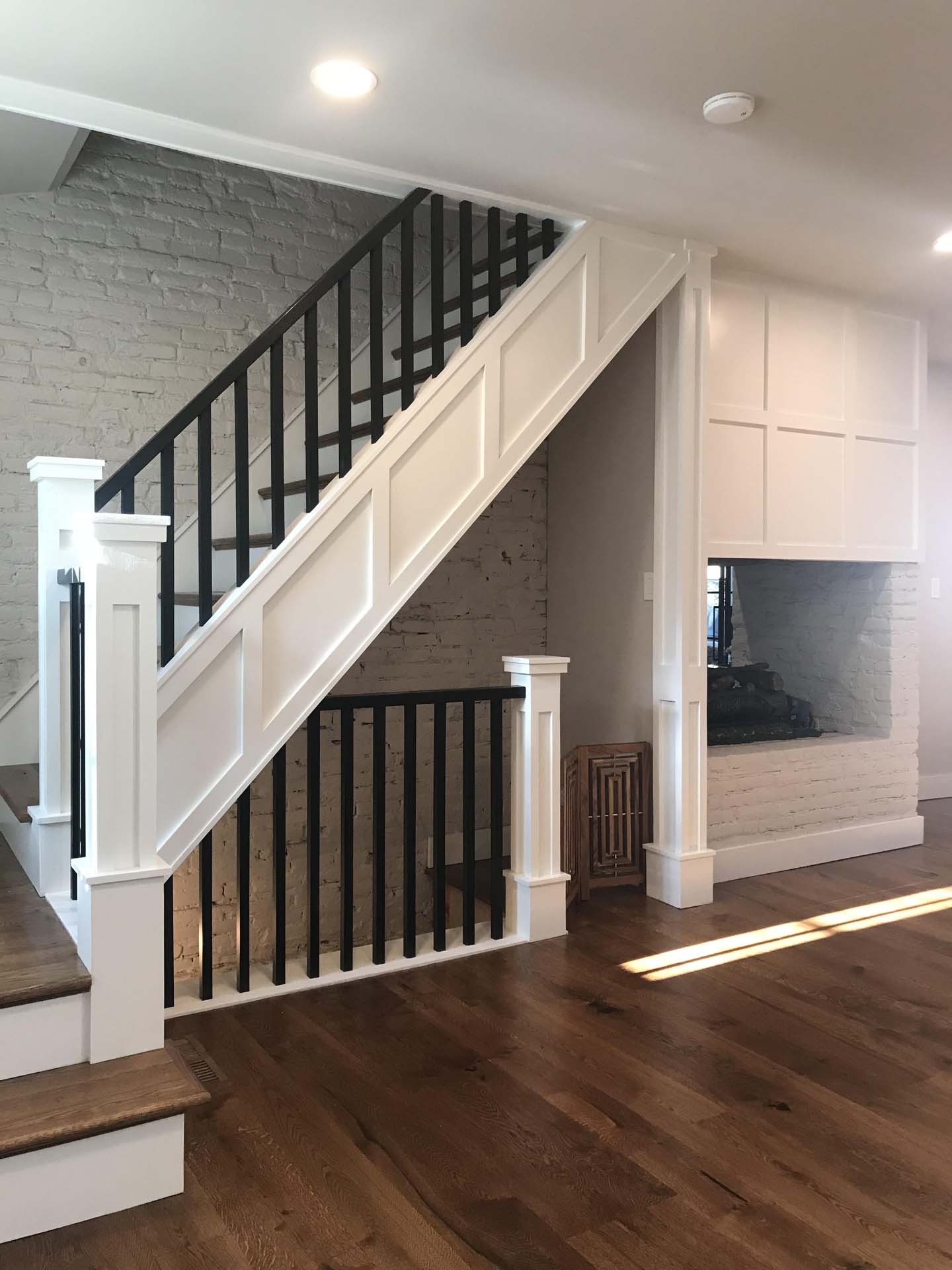 white stair case with black railing leading to hardwood floor